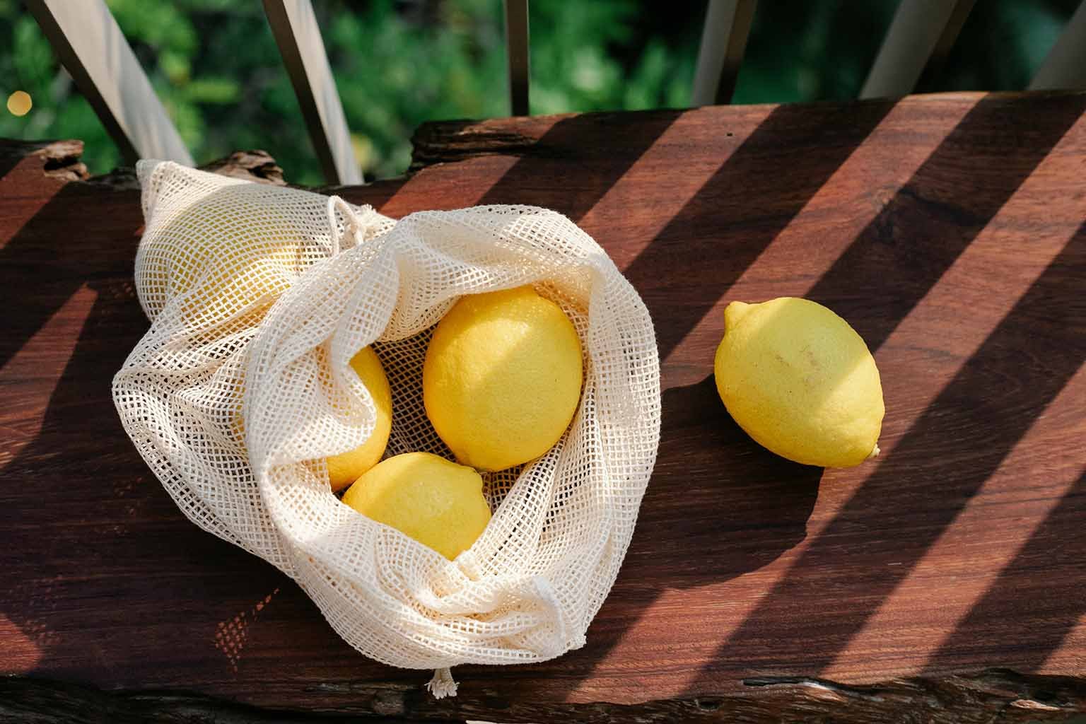Close-up of fresh produce like apples and onions inside a mesh bag