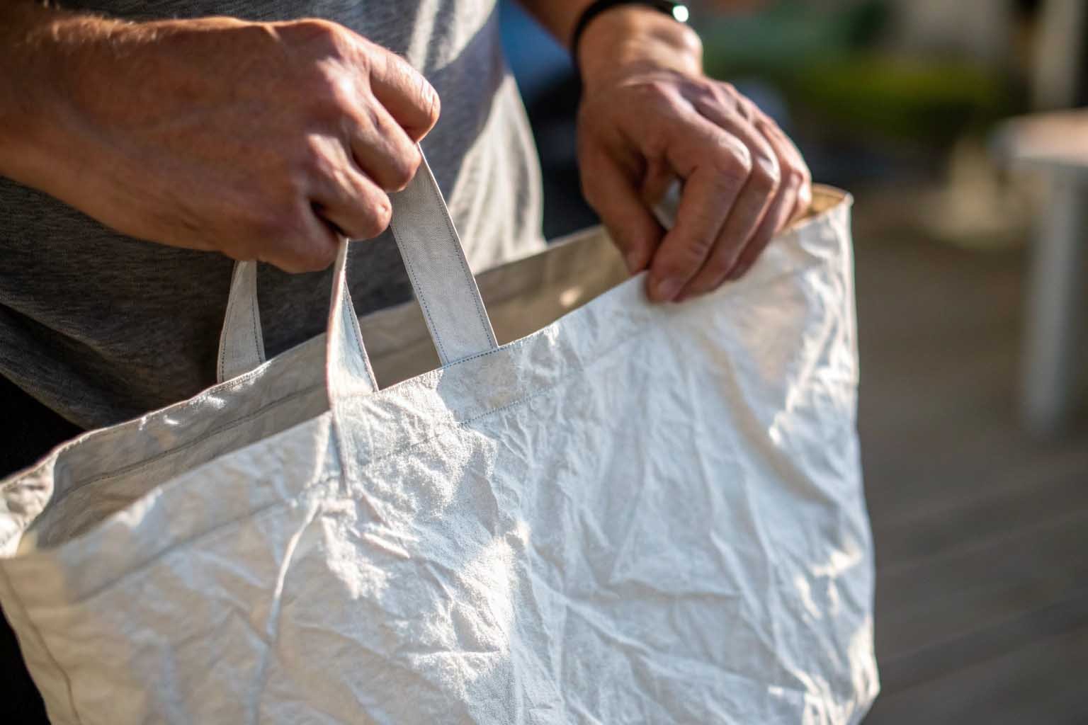 Person looking thoughtfully at a crinkled Tyvek tote bag