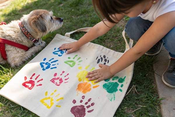 A child and a dog making paw prints on a canvas bag