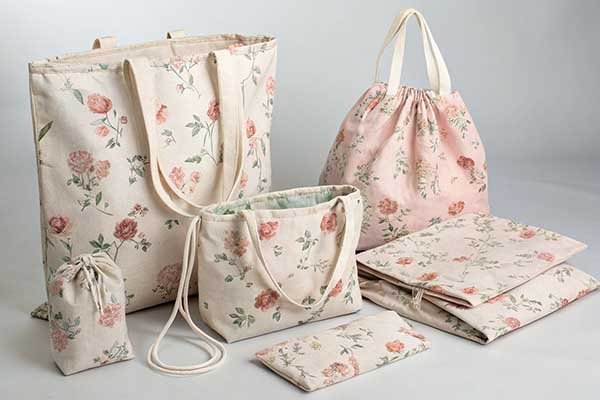 A collection of tote bags, drawstring pouches, and fold-up bags all featuring the same floral fabric pattern.
