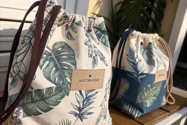 A close-up of a brand label sewn onto a drawstring bag, with a matching tote in the background—showing how using one print across products reinforces brand identity.