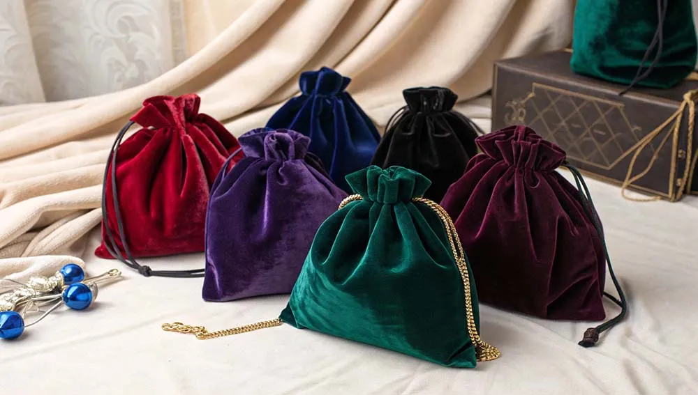 A collection of velvet drawstring bags in various colors displayed on a soft surface