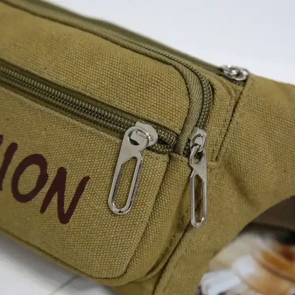 Close-up image of a khaki canvas waist bag with two zippers showing the letters 'ION' printed on it.