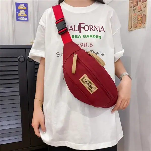Person wearing a white California-themed t-shirt and a red shoulder bag.