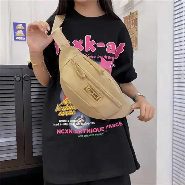 Person wearing a black shirt with NCXK-Art pink graphics and holding a beige fashion bag across the shoulder.