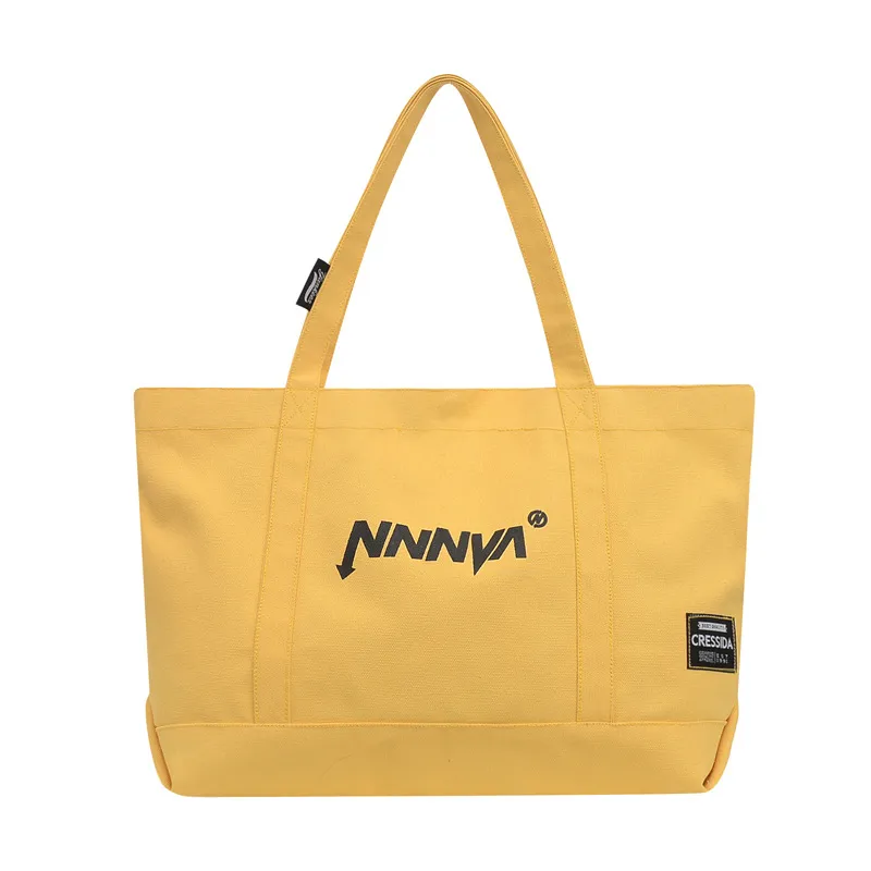 A yellow NNNVA canvas tote bag with black label and logo.
