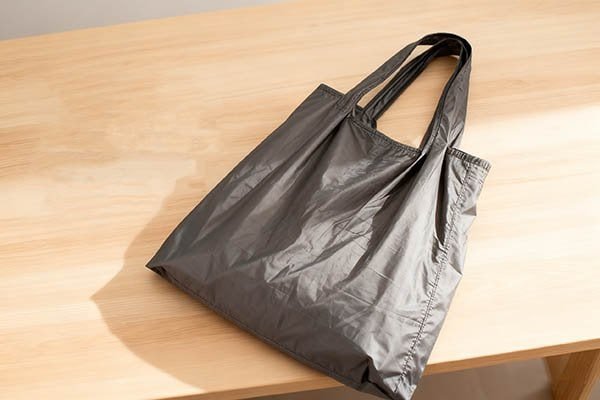 A gray nylon foldable bag placed on a wooden table