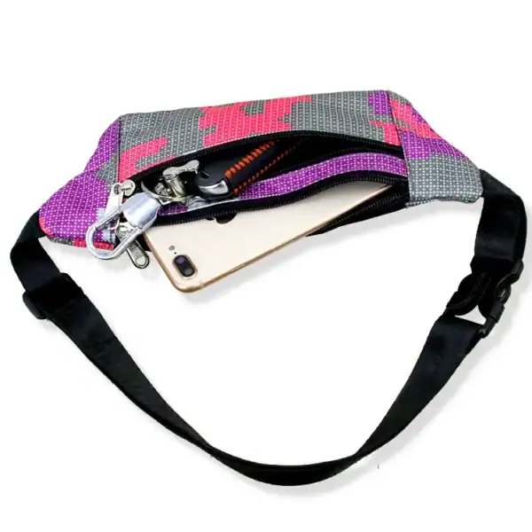 A pixel art style waist bag with a zipper, showing a smartphone, keys, and other small items inside. The bag has a colorful design and an adjustable black strap.