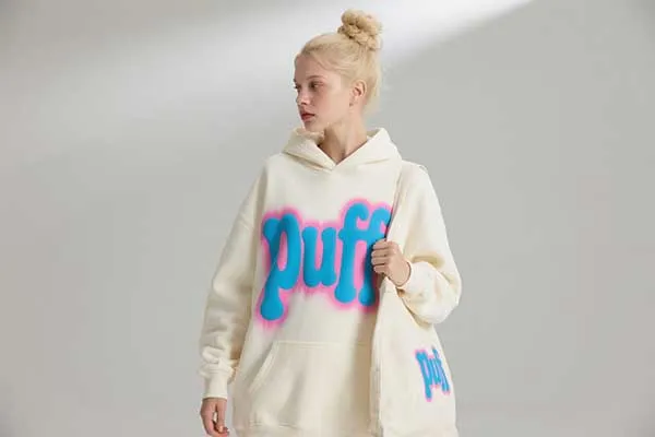 A model wearing a hoodie with a large, puffy 3D printed logo on the chest.