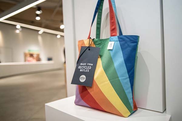 A colorful, lightweight RPET tote bag with a small tag indicating it is made from recycled bottles.