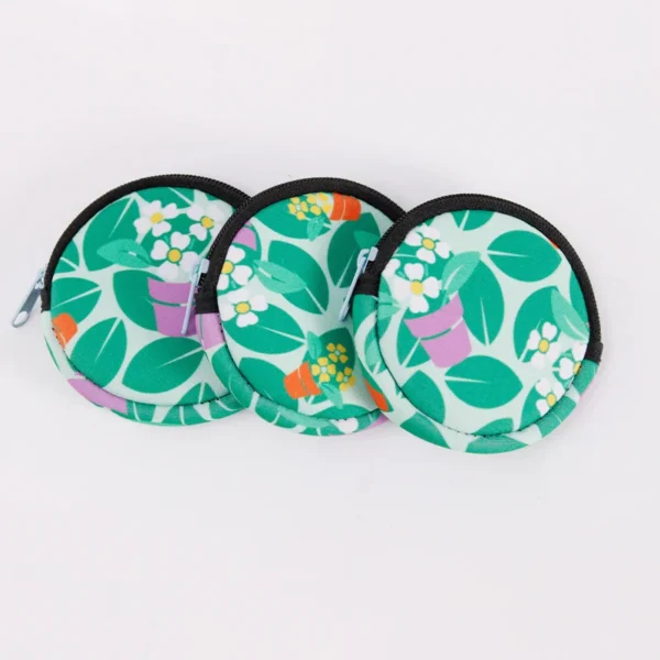 Three colorful round coin purses featuring plant designs on a green background.