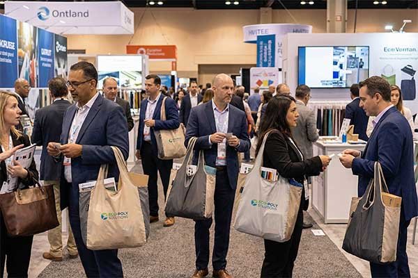Busy trade show floor with attendees carrying bags