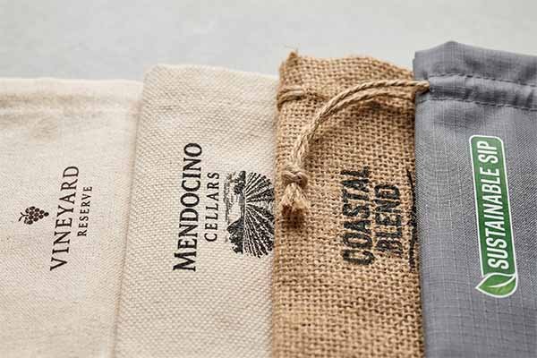Close-up of sustainable wine packaging materials including custom cotton, canvas, jute, and RPET bags.