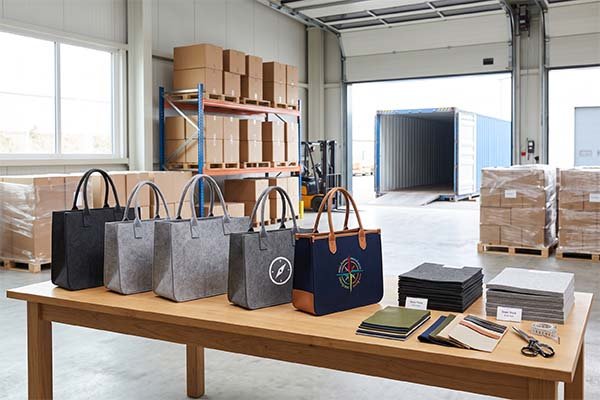 Finished custom felt bags with and without logos, along with various material swatches and handle options, showing cost-saving choices.