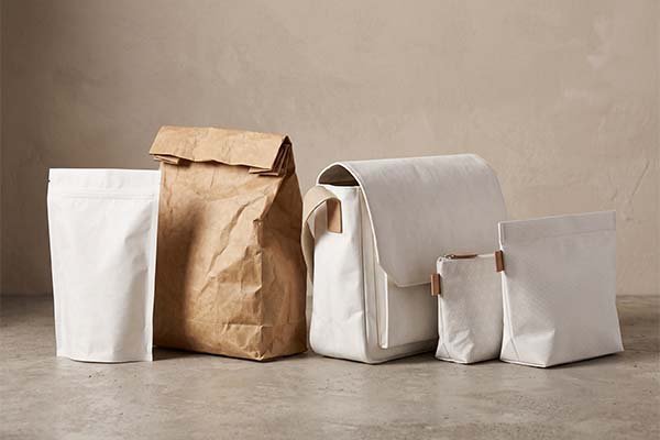 Visual comparison between white Tyvek stand-up pouches, zipper bags, and traditional brown kraft paper bags, highlighting the texture differences of various packaging materials.
