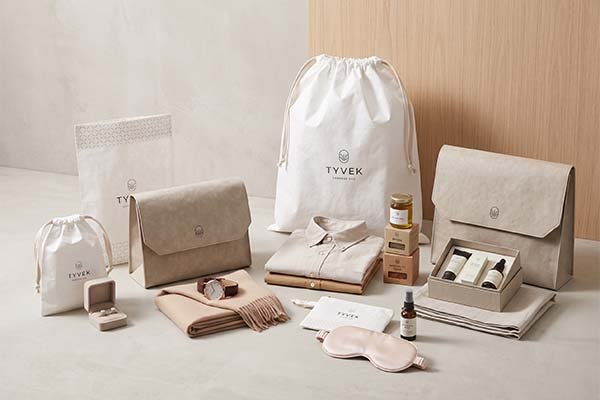 Custom printed Tyvek packaging bags applied to various premium products, including neatly folded shirts, skincare sets, a jewelry box, and spices.