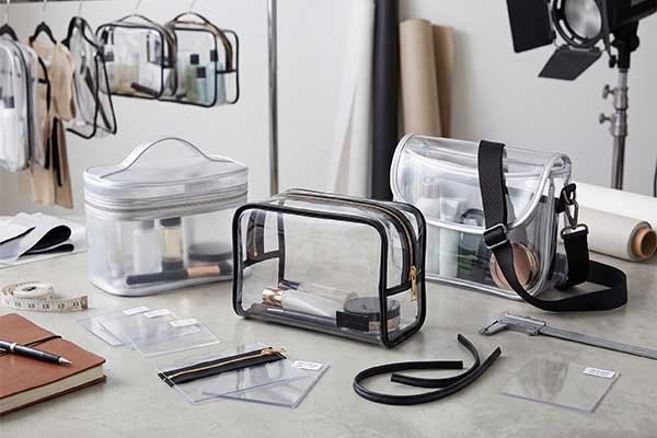 Custom clear bag manufacturing and R&D studio, displaying sample prototypes, zipper accessories, material thickness swatches, and calipers for B2B quality control.