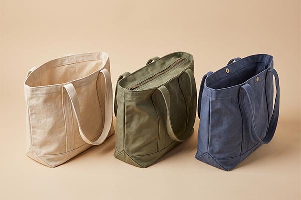 Three custom canvas tote bags displaying open-top, zipper, and magnetic snap closure types side-by-side.